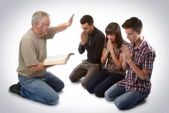 Preacher leading three young souls in prayer to receive Jesus